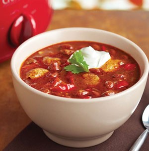 Cup of chipotle pork chili, garnished with sour cream and cilantro