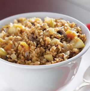 White bowl filled with rice, apples, and dried fruit