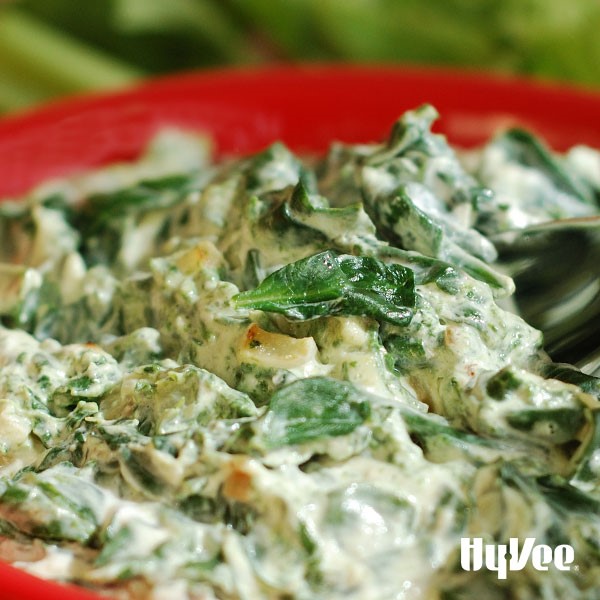 Red bowl filled with spinach and artichoke dip