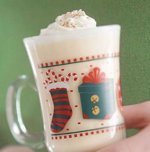 Decorated glass Christmas mug filled with orange nog and topped with whipped cream