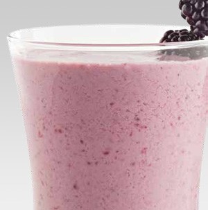 Glass filled with pink smoothie and garnished with blackberries
