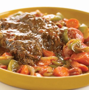 Pot roast with sliced squash, carrots, peppers and onions in a yellow bowl