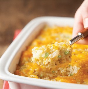White casserole dish filled with rice, cheese, and finely diced hatch peppers