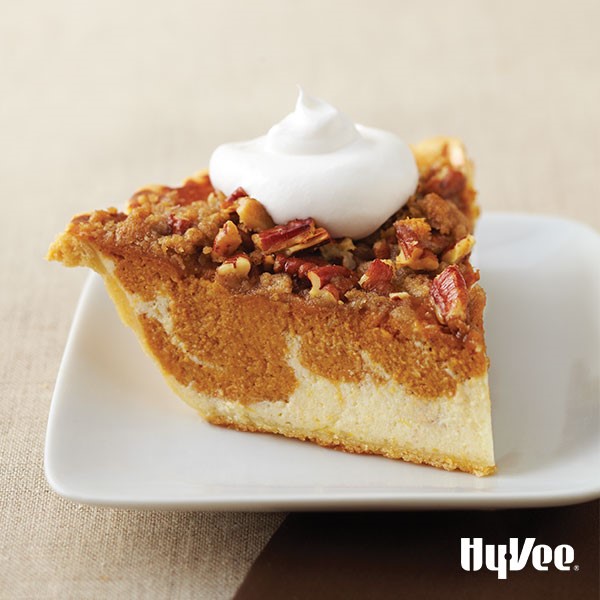 Pumpkin pie swirled with cream cheese and chopped pecans and whipped cream on top