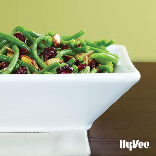 Green beans, sliced almonds, and dried cranberries in white serving dish