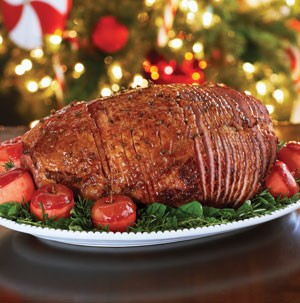 Glazed and sliced holiday ham on a bed of mixed greens