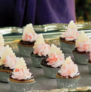 Mini cupcakes in aluminum tins topped with chocolate and pink and white frosting