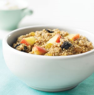 Quinoa oatmeal with chopped apples and dried fruit in a white bowl