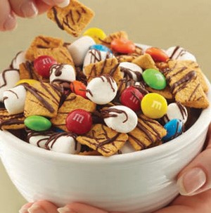 Bowl filled with honey graham crunch cereal, M&M's, and mini-marshmallows, and drizzled in milk chocolate