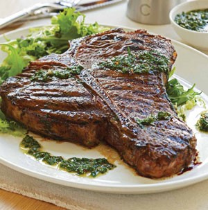 Grilled t-bone steak garnished with chimichurri sauce with mixed salad on the side