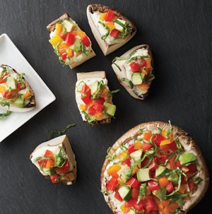 Stuffed portabella bites topped with tomato, bell pepper, avocado and basil