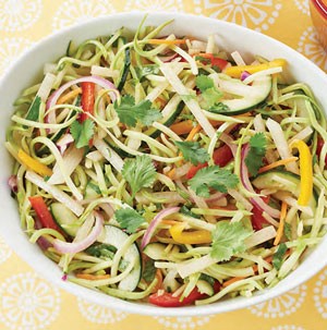 Thinly sliced vegetables in a white bowl topped with fresh cilantro leaves