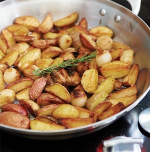 Skillet filled with roasted potato wedges and garnished with fresh rosemary sprig