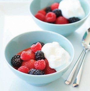 Light blue bowls filled with fresh mixed berries and whipped topping