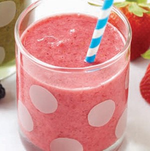 White polka-dot glass filled with pink berry smoothie with a blue-and-white striped straw