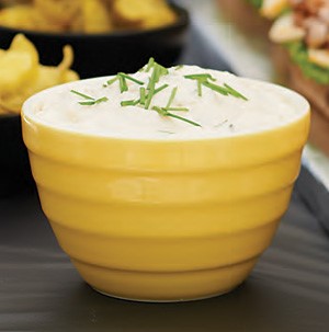 Yellow bowl of Creamy Horseradish Sauce, garnished with fresh Chives