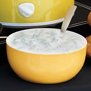 Creamy white tazatziki sauce in a small yellow bowl