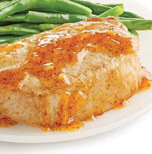 Orange and Dijon mustard glazed pork chops on plate with fresh green beans