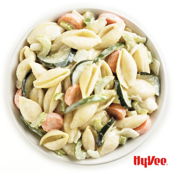 Pasta salad mixed with cucumber, onion, carrots, radishes and green bell pepper