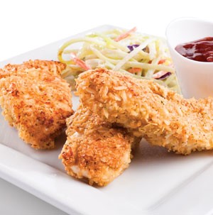 Three breaded chicken tenders on a plate with coleslaw and small dish of ketchup