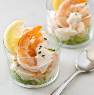 Spicy warm shrimp cocktail served in glass cup with spoon