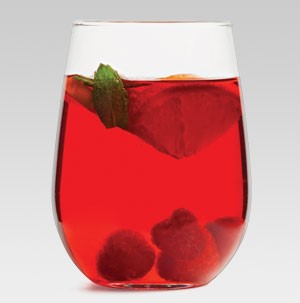 Glass of sparkling red wine sangria filled with fresh raspberries and garnished with an orange slice and mint leaf