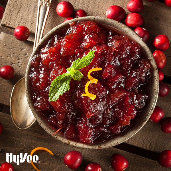 Cranberry sauce garnished with orange peel and fresh mint surrounded by fresh cranberries