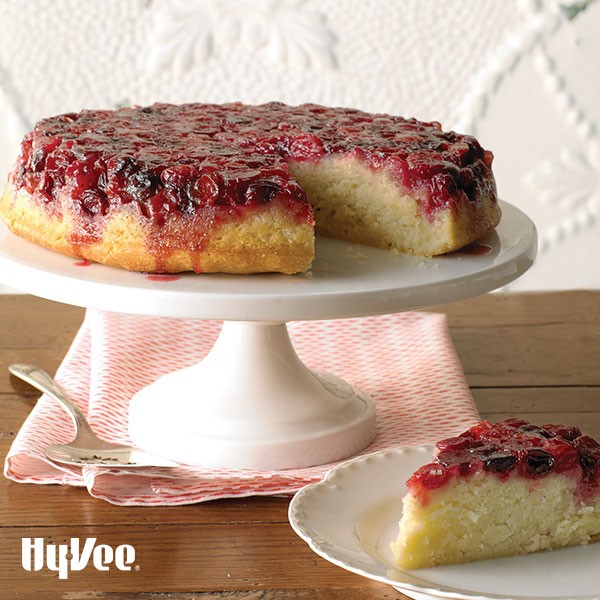 Slice of cranberry upside-down cake next to platter of cake