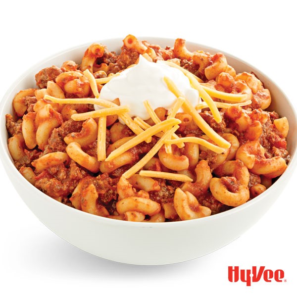 Bowl of chili macaroni and cheese, topped with sour cream and shredded cheese