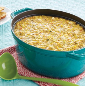 Teal Dutch oven filled with corn chowder next to a green ladle on a red napkin