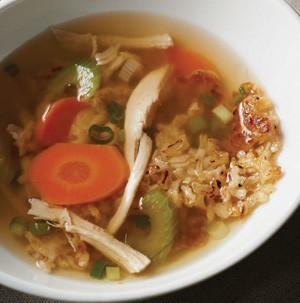 Bowl of sizzling rice soup mixed with shredded chicken, carrots, celery and onion