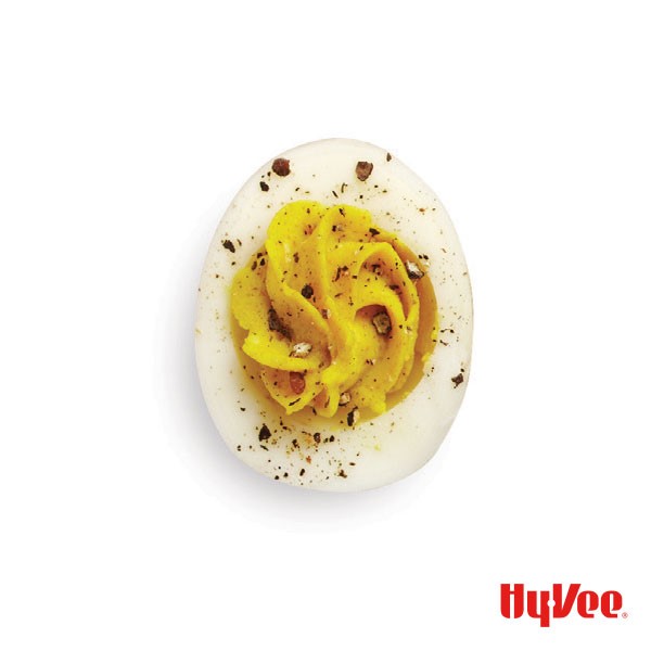 A curried deviled egg topped with freshly cracked black pepper