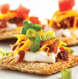 Cracker topped with mayo, bacon, cheese, green onions and tomato