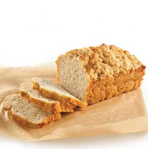 Loaf and slices of buttery beer bread on parchment paper