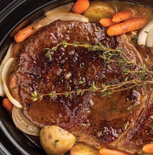 Pot roast with onions, carrots, potatoes and thyme in slow cooker
