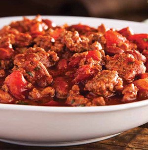 White bowl filled with cooked ground meat and diced tomatoes in a tomato sauce