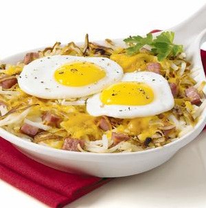 Hashbrowns topped with diced ham, melted cheese, and two fried eggs