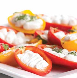 Halved mini bell peppers filled with sour cream and garnished with fresh herbs