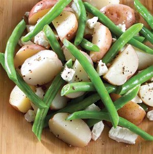 Bowl filled with potato chunks, fresh green beans and feta cheese crumbles