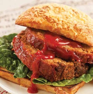 Bun topped with lettuce leaf, two slices of meatloaf and garnished with ketchup
