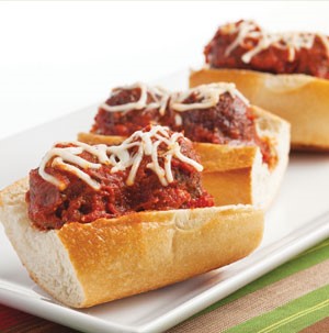 Open hoagie rolls topped with warm meatballs, spaghetti sauce and shredded mozzarella