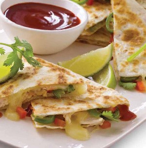 Plate of barbecue chicken quesadillas served with cilantro, lime and bowl of barbecue sauce