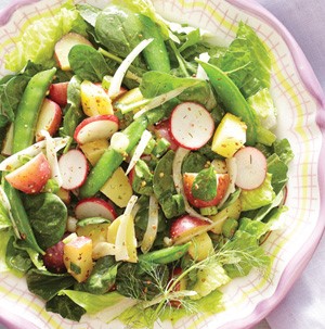 Bowl of salad mixed with new potatoes, snap peas, radishes and onion