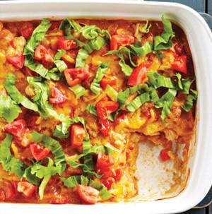 Casserole dish of cheesy chicken enchilada bake with a piece cut out