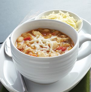 Cup of chicken bean soup, topped with melted cheese