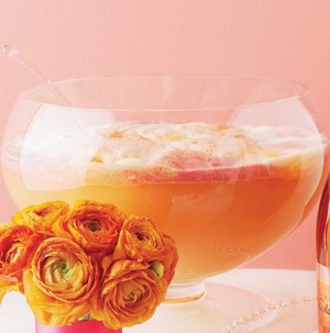 Glass bowl filled with orange and pink sherbet next to orange roses