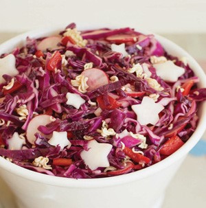 Cup of coleslaw with red cabbage, red pepper strips, ramen noodles and garnished with radish-shaped stars