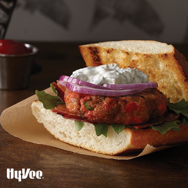 Salmon burger served between two slices of grilled bread and topped with onions and dill sauce