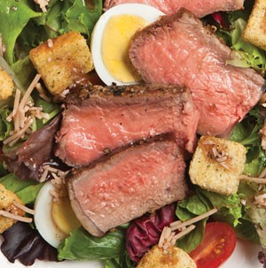 Peppered steak over plate of salad