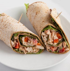 Flour tortillas wrapped around sliced turkey, red peppers, and lettuce